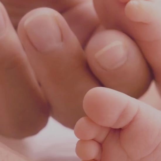 une main de maman qui caresse les pieds de son bébé