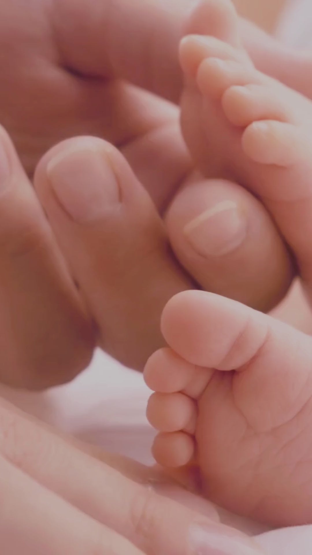 une main de maman qui caresse les pieds de son bébé